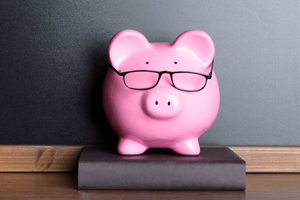 Piggy Bank With Eye Glasses On Book